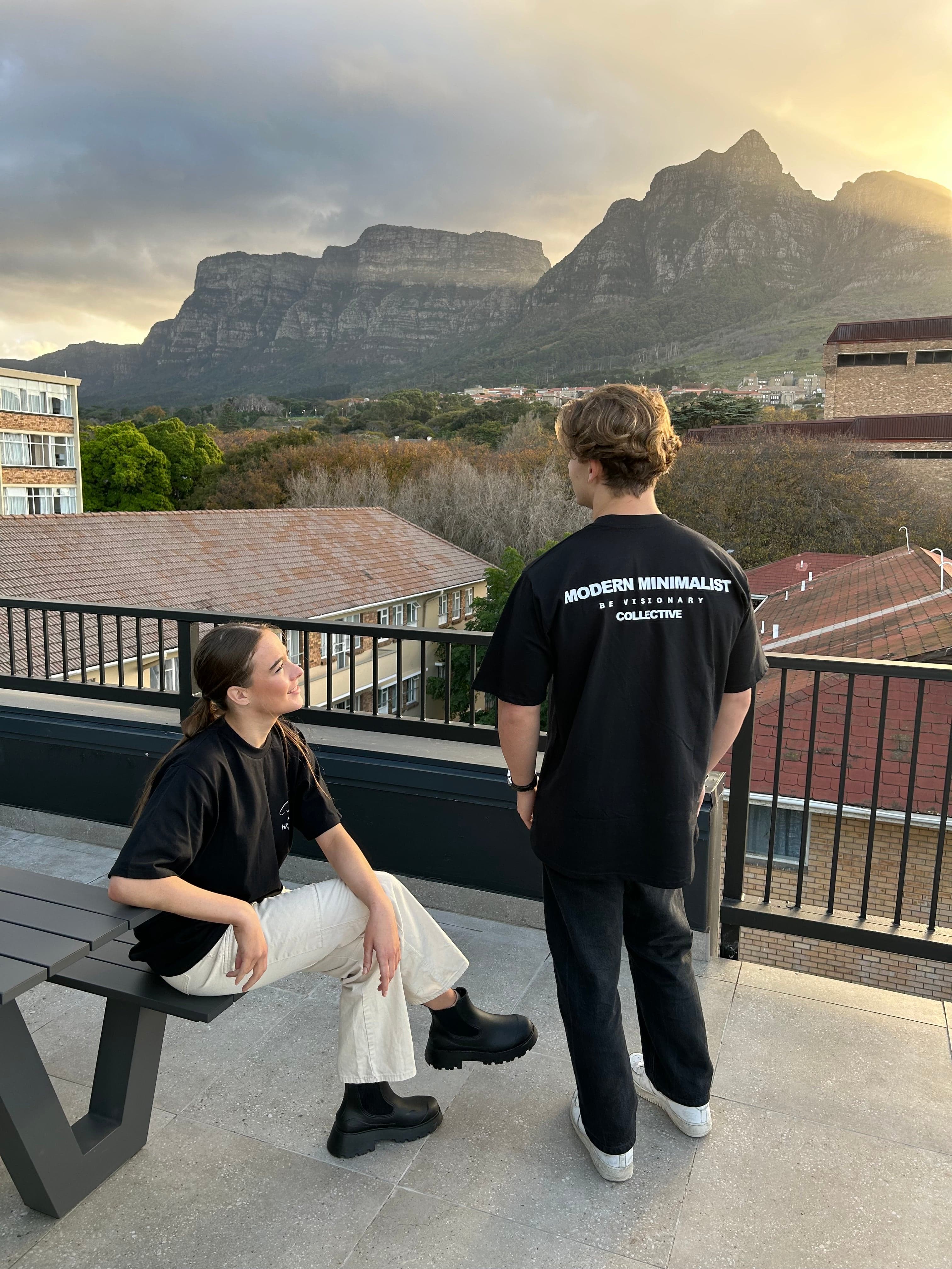 A person wearing a DTF-printed black branded T-shirt at an outdoor viewpoint