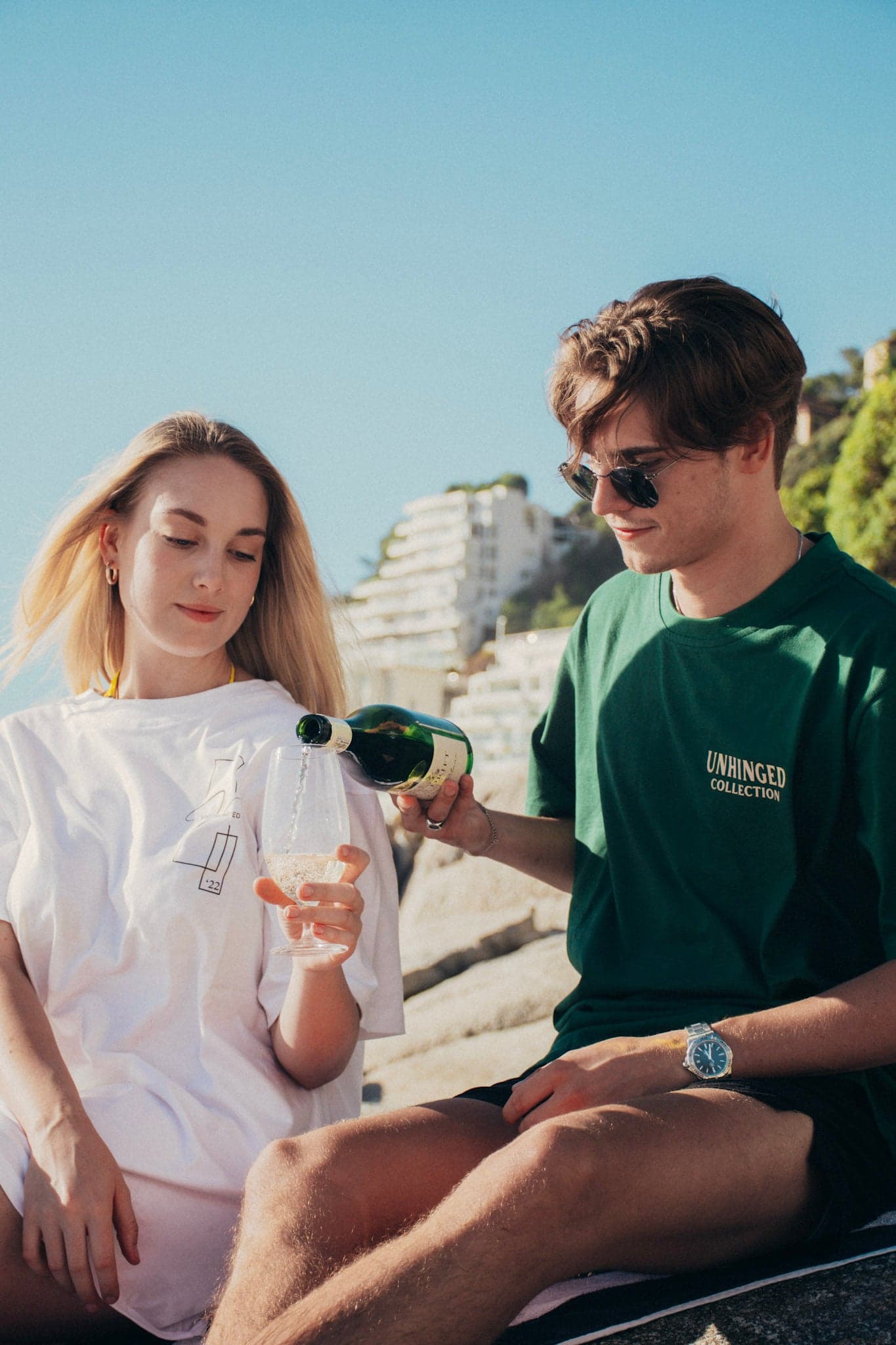 Two people wearing branded Vision Fashion Collective T-shirts at an outdoor viewpoint